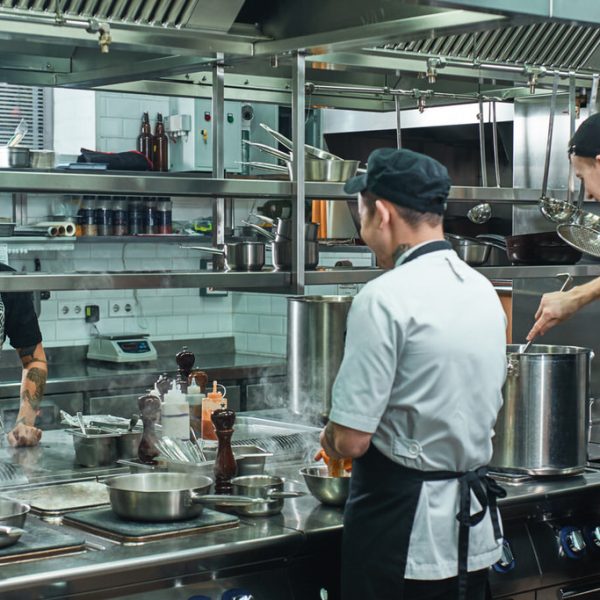 Cooking process. Professional team of chef and two young assistant preparing food in a restaurant kitchen