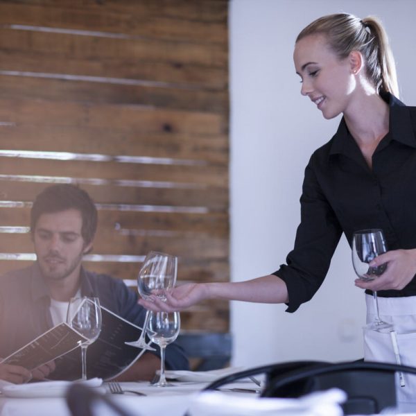 Waitress setting table with wine glass for customers
