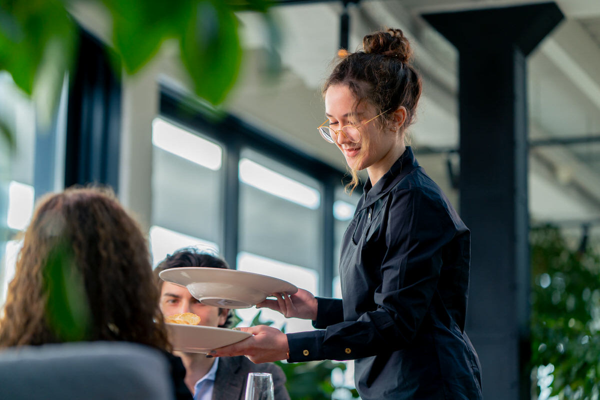 a girl waiter serves orders to guests the concept of hospitality and service in high-class restaurant