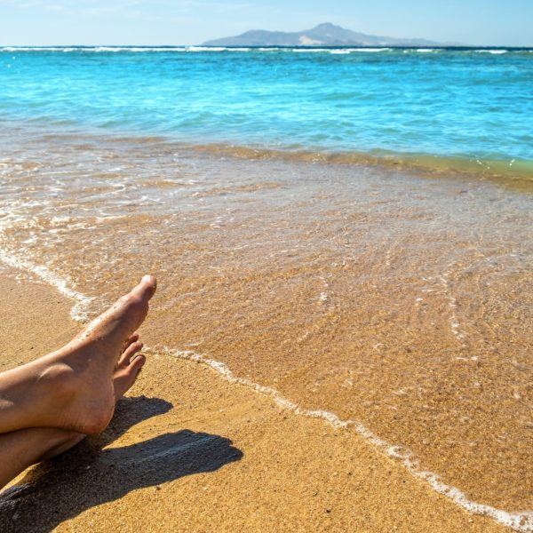 Long slim young woman legs relaxing lying down and sunbathing on