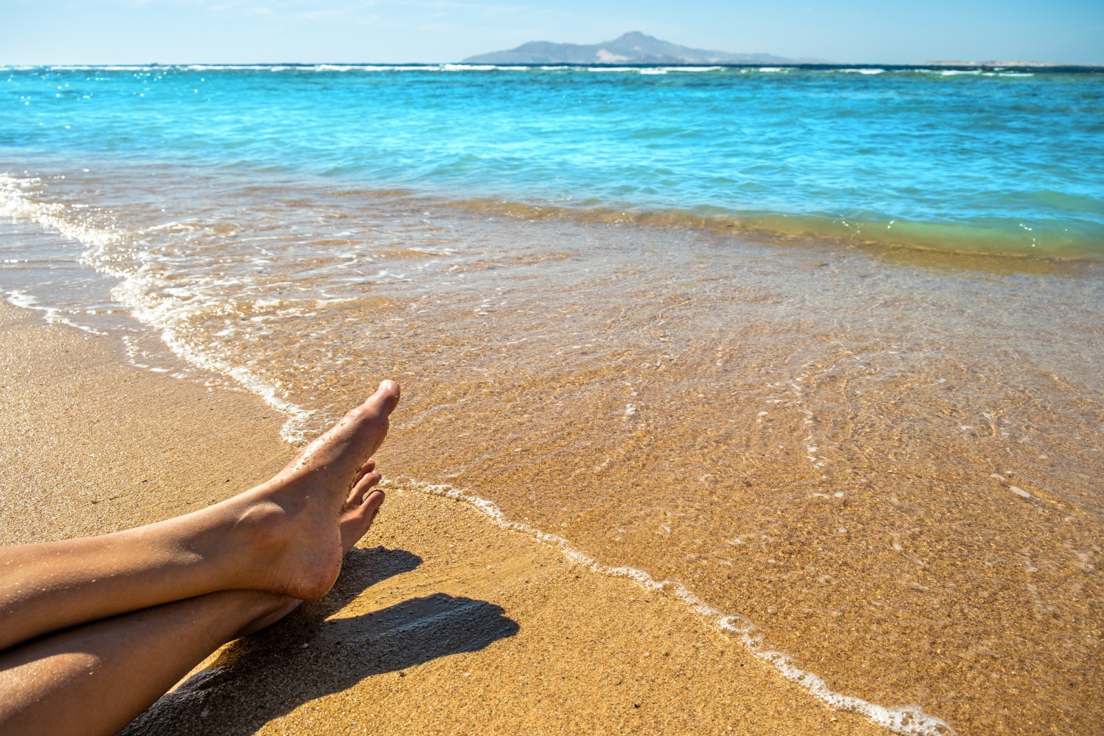 Long slim young woman legs relaxing lying down and sunbathing on